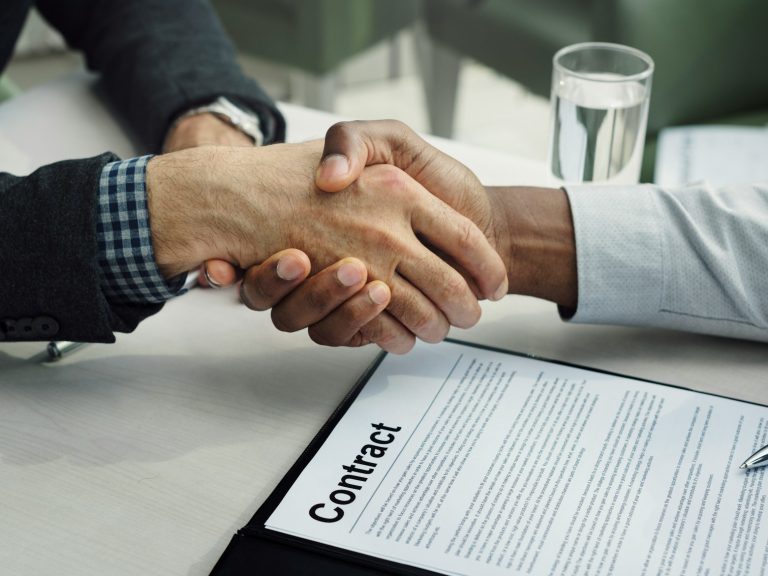 Manos estrechándose y contrato