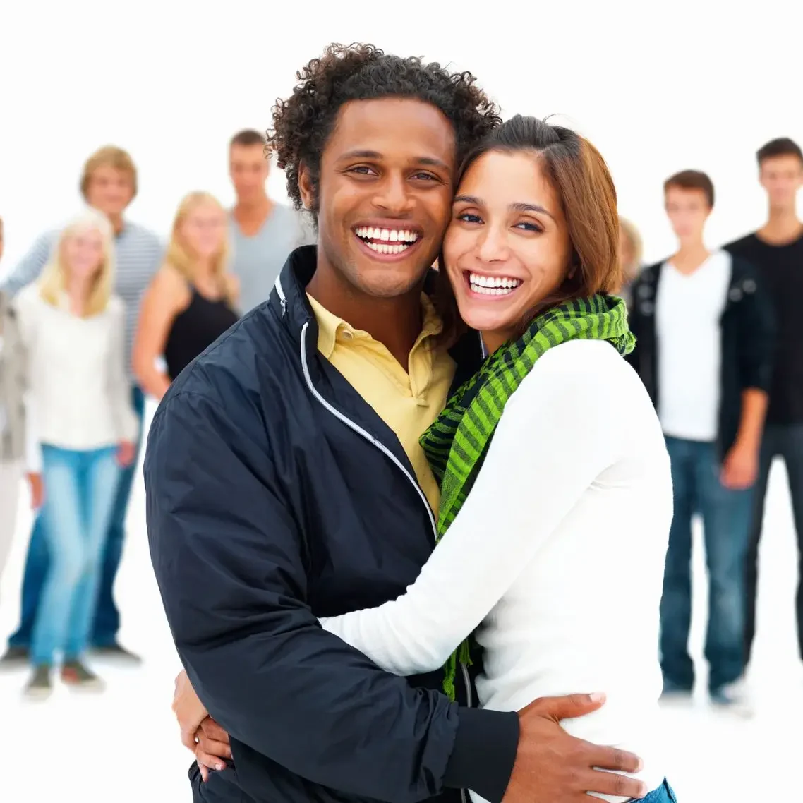 Pareja sonriendo en primer plano, con un grupo de personas al fondo.