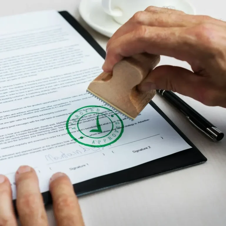 Mano aplicando un sello sobre un documento con un círculo verde y una marca de verificación.